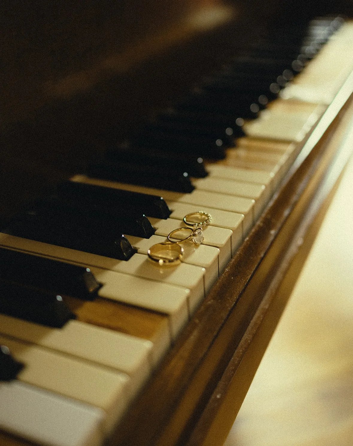 Three rings resting on the keys of an old piano.