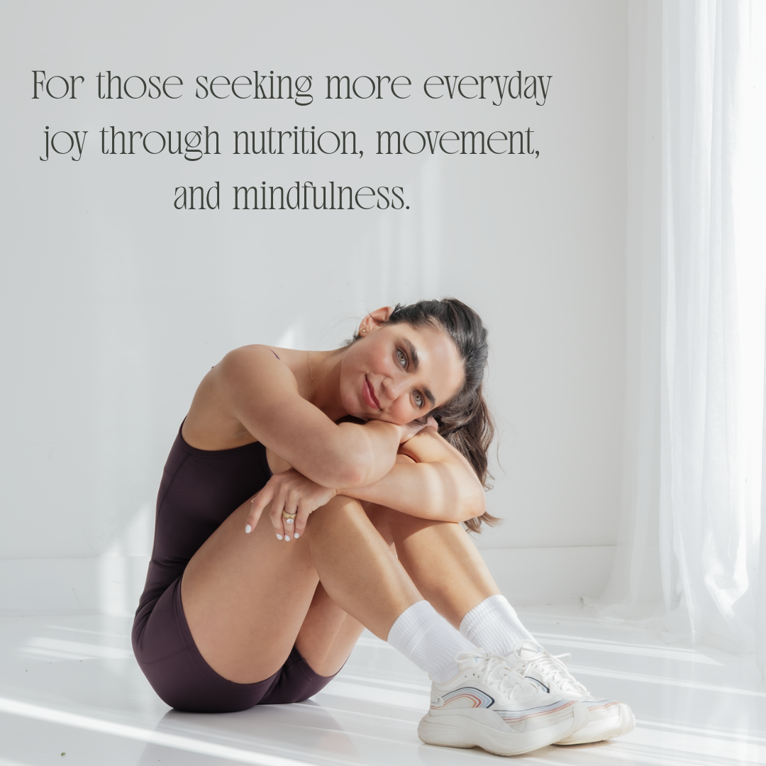 Woman with brown hair in a black sleeveless top and shorts sitting on a white floor, hugging her knees, near white curtains, with text about joy through nutrition, movement, and mindfulness.