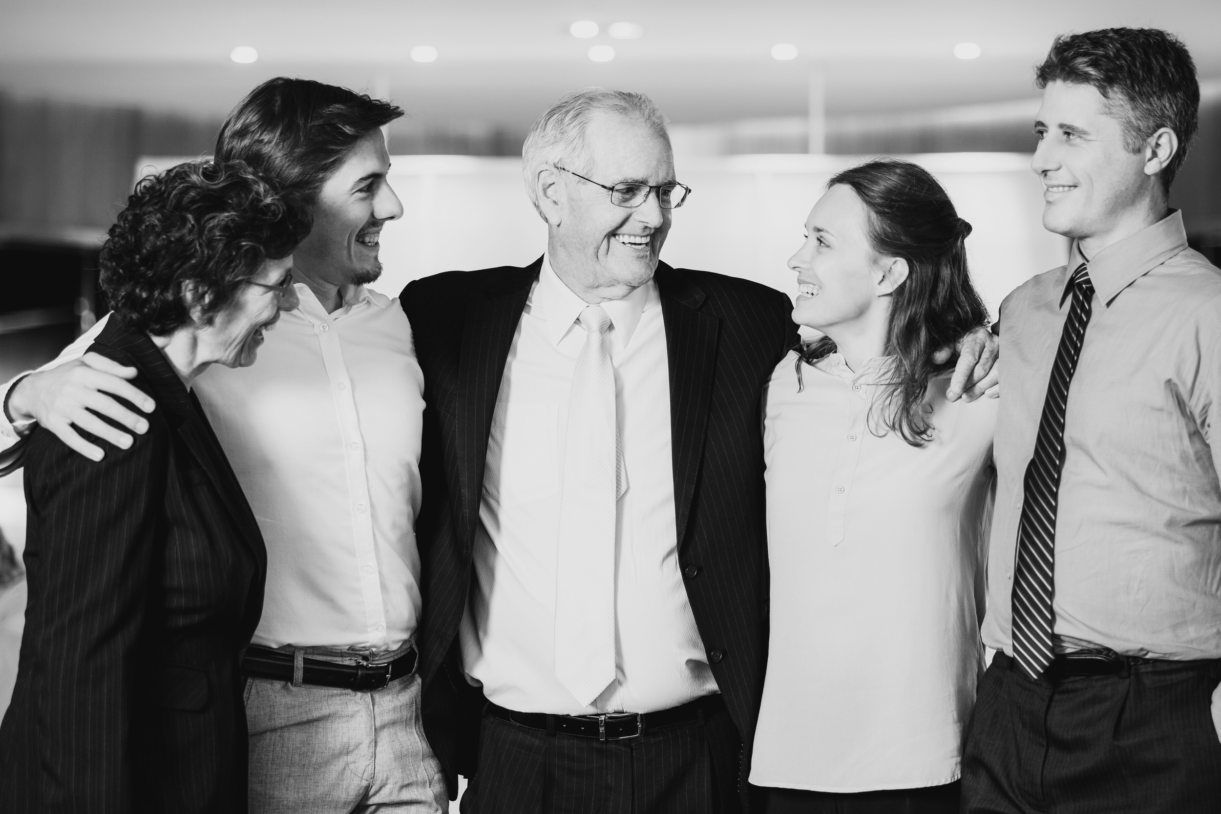 Group of six diverse people smiling and talking together in a professional setting.