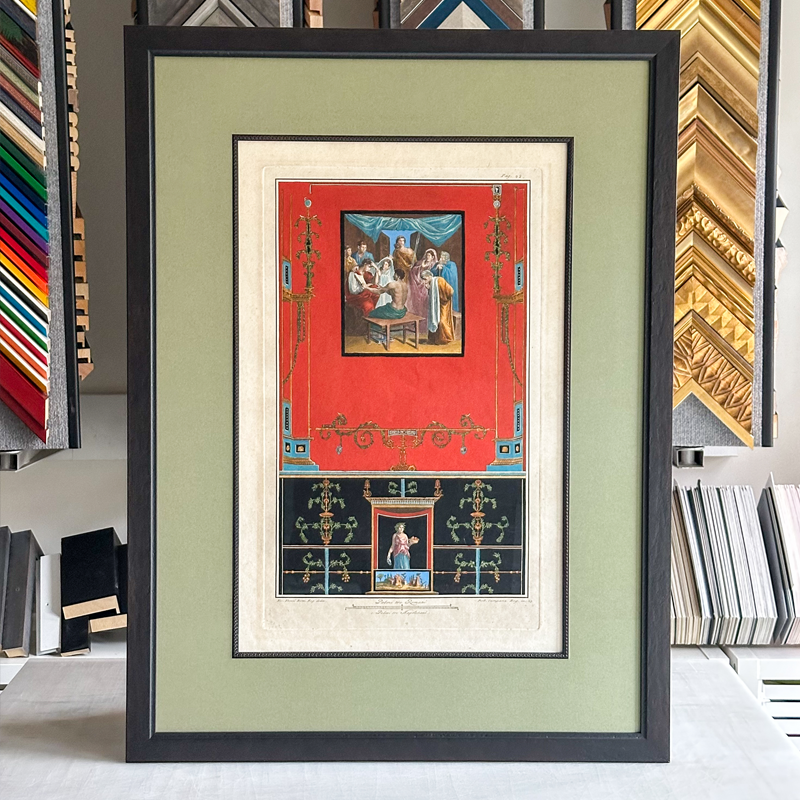 Framed artwork featuring a colorful interior scene, with a larger image of a gathering of people on a red background at the top, and a smaller, central image of a religious figure with decorative elements on a black background at the bottom.