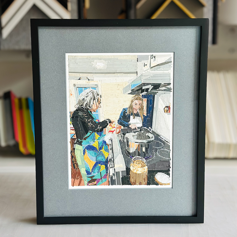 Framed painting of two women cooking in a kitchen, one stirring a pot and the other preparing food.