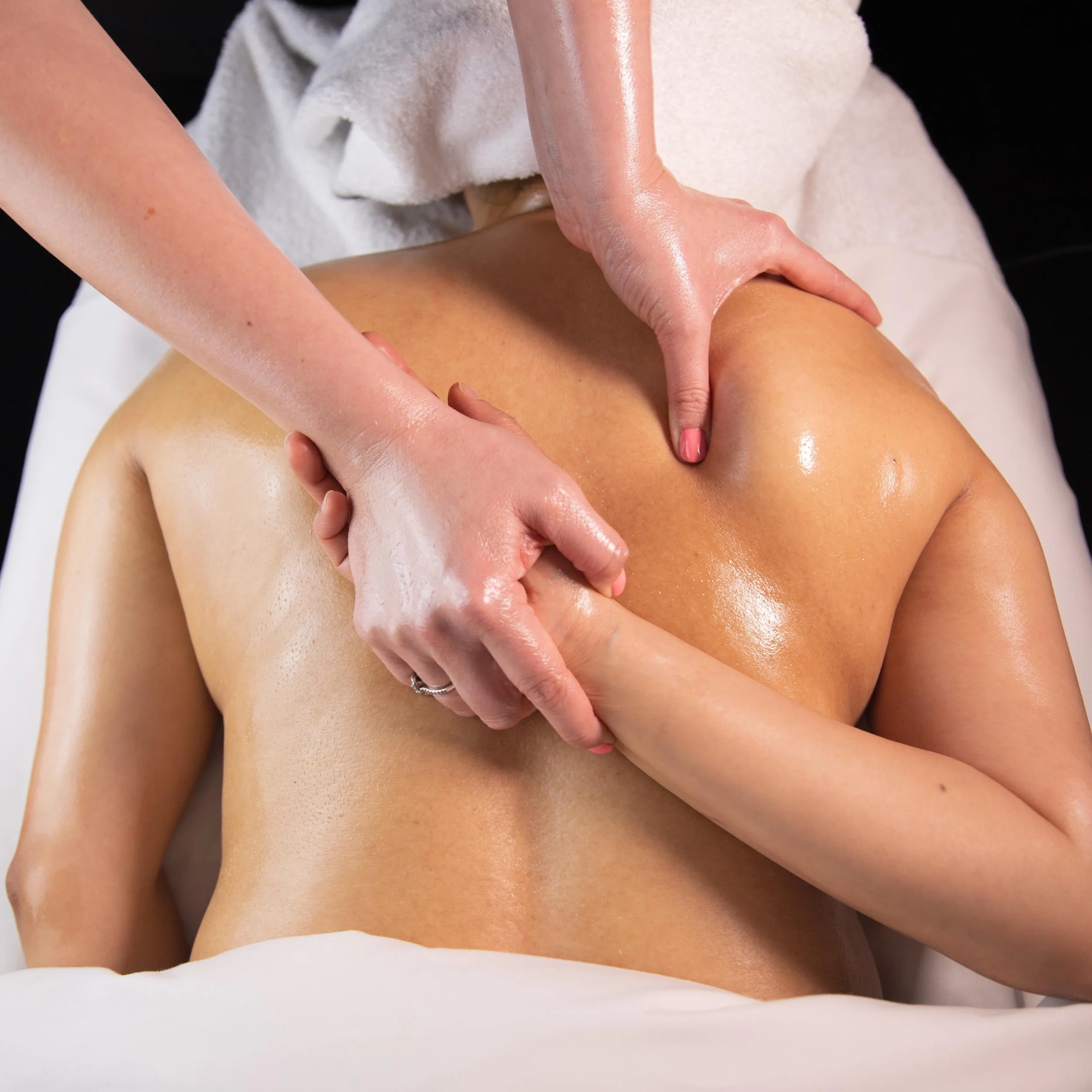 A person receiving a back massage with oil, lying face down on a massage table.