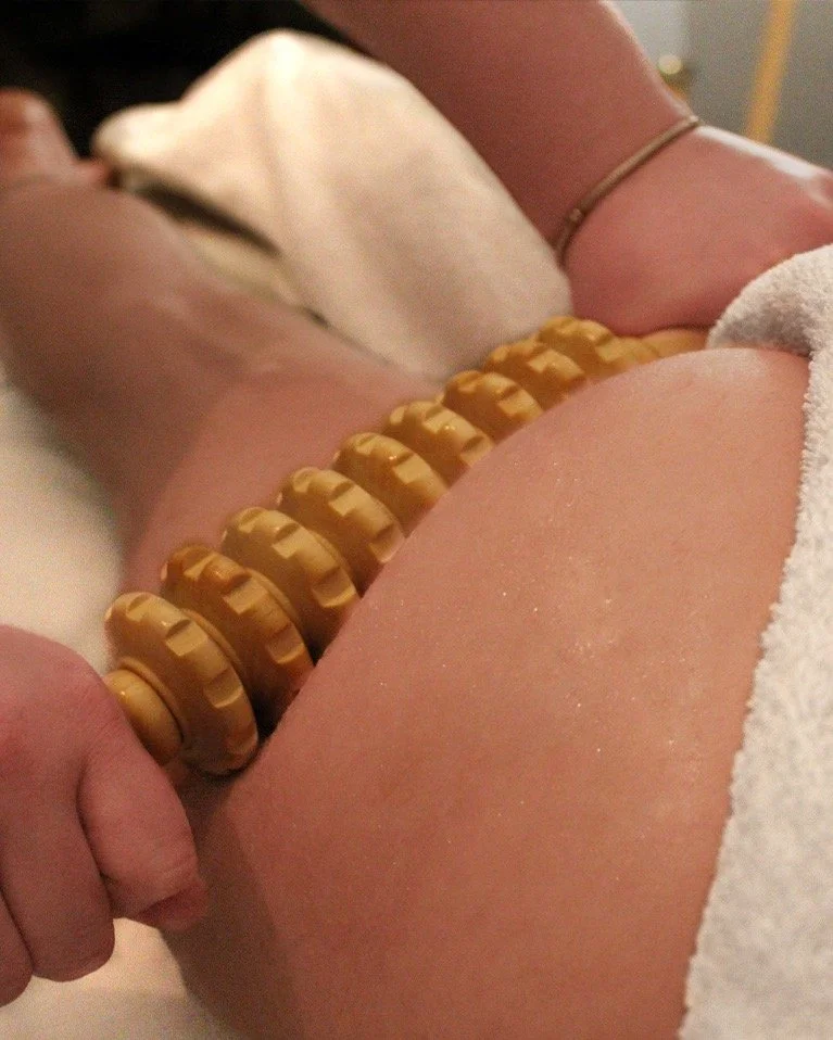 A person holding a large, segmented, yellow object against their thigh, with a white towel and a dog in the background.
