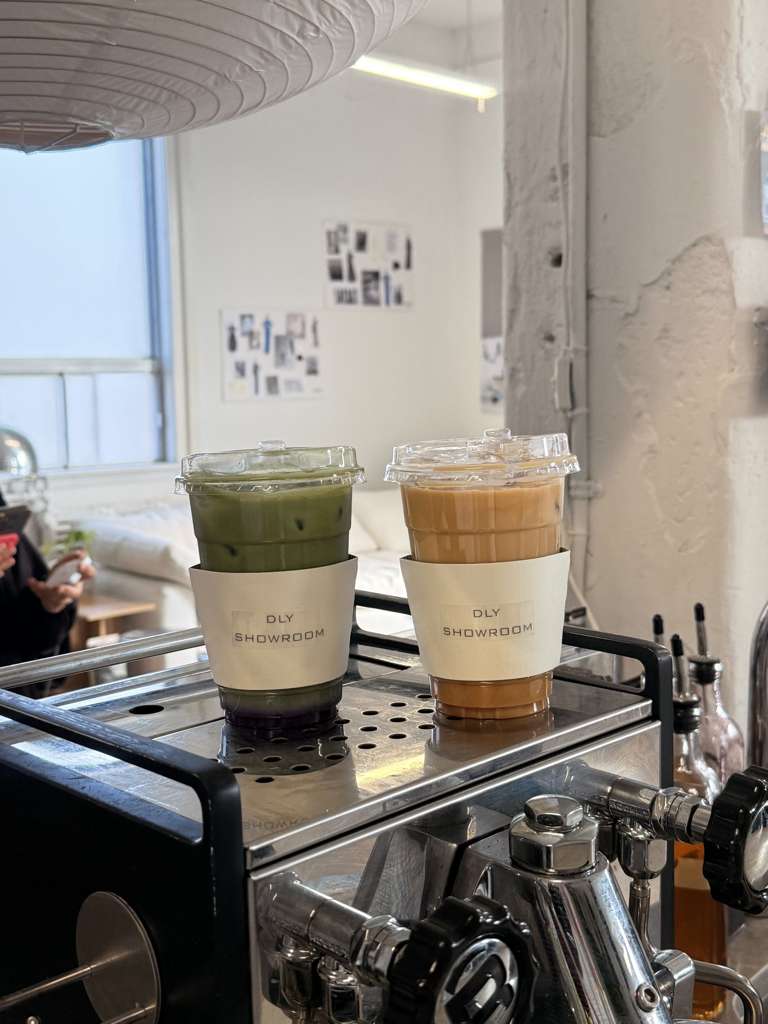 A signature iced matcha and a specialty iced latte from Café Apéro resting on a professional stainless steel espresso machine. This duo of colorful iced drinks was served at the Daleeyah.co fashion brand activation in Ottawa, Ontario.