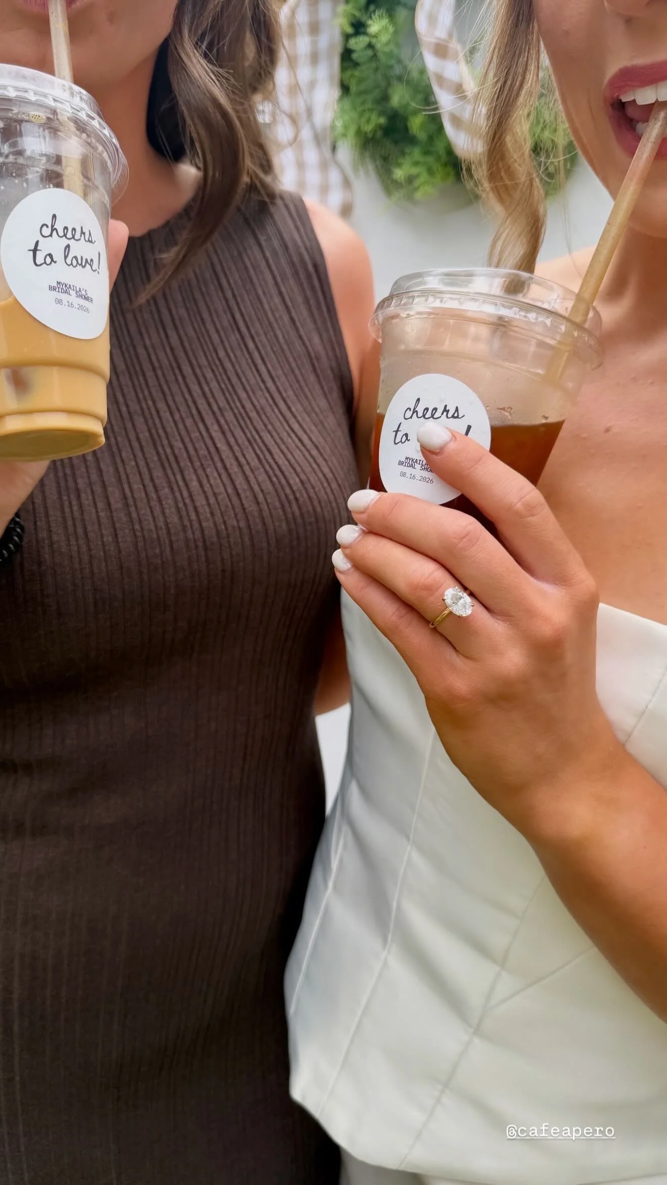 A newlywed couple sitting at a wedding reception table decorated with white flowers in Ottawa, holding signature handmade iced lattes made my the turn-key mobile espresso service made by Cafe Apero.