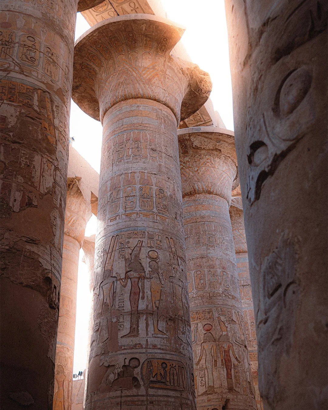 Ancient Egyptian temple interior with large, decorated columns inscribed with hieroglyphics and images of Egyptian gods and pharaohs.