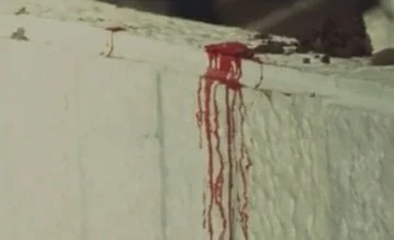 Bloodstains on a white wall with streaks down the side.