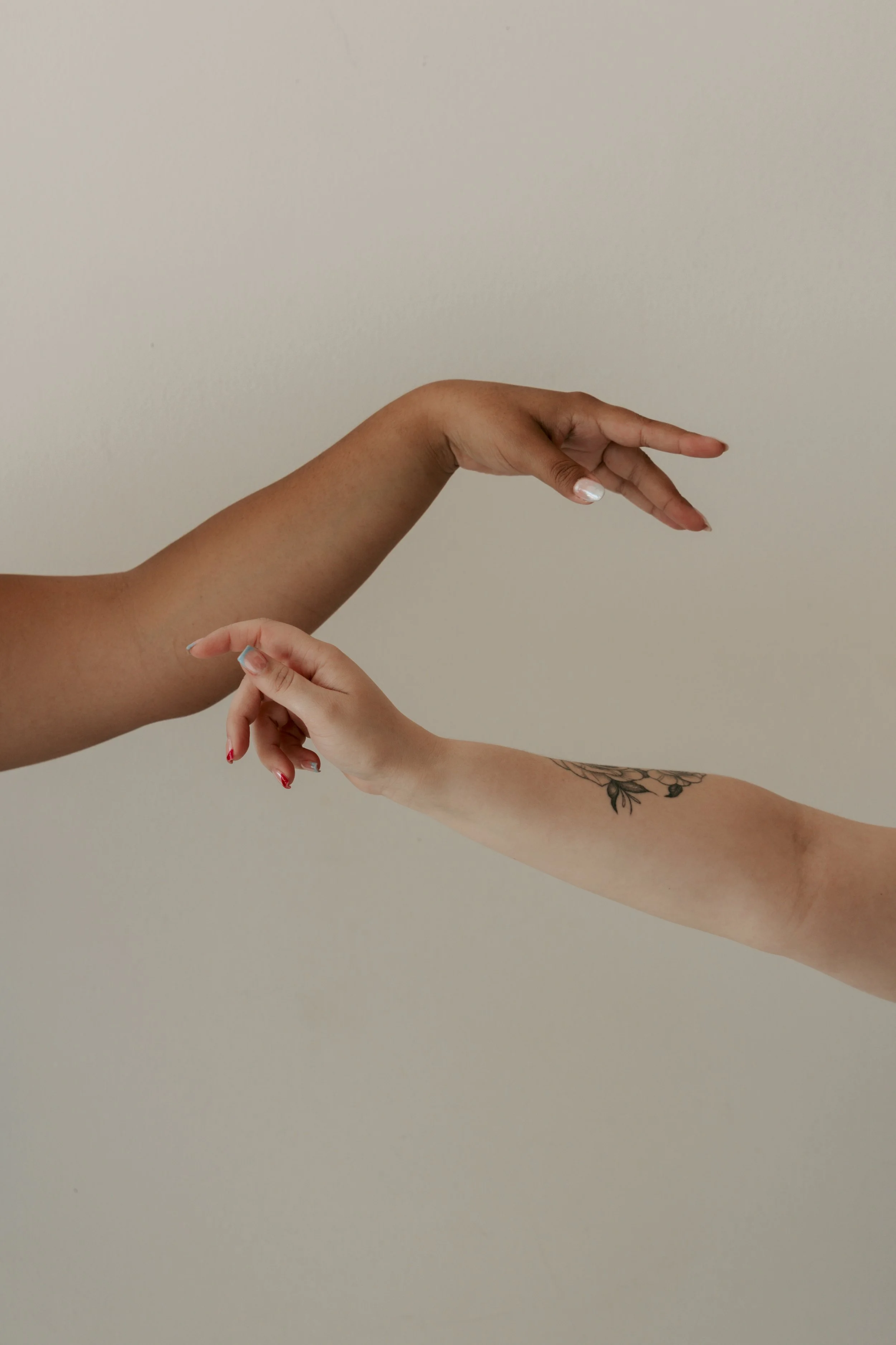 Two hands touching, one larger with a darker skin tone, and the other smaller with a lighter skin tone, against a plain light background.