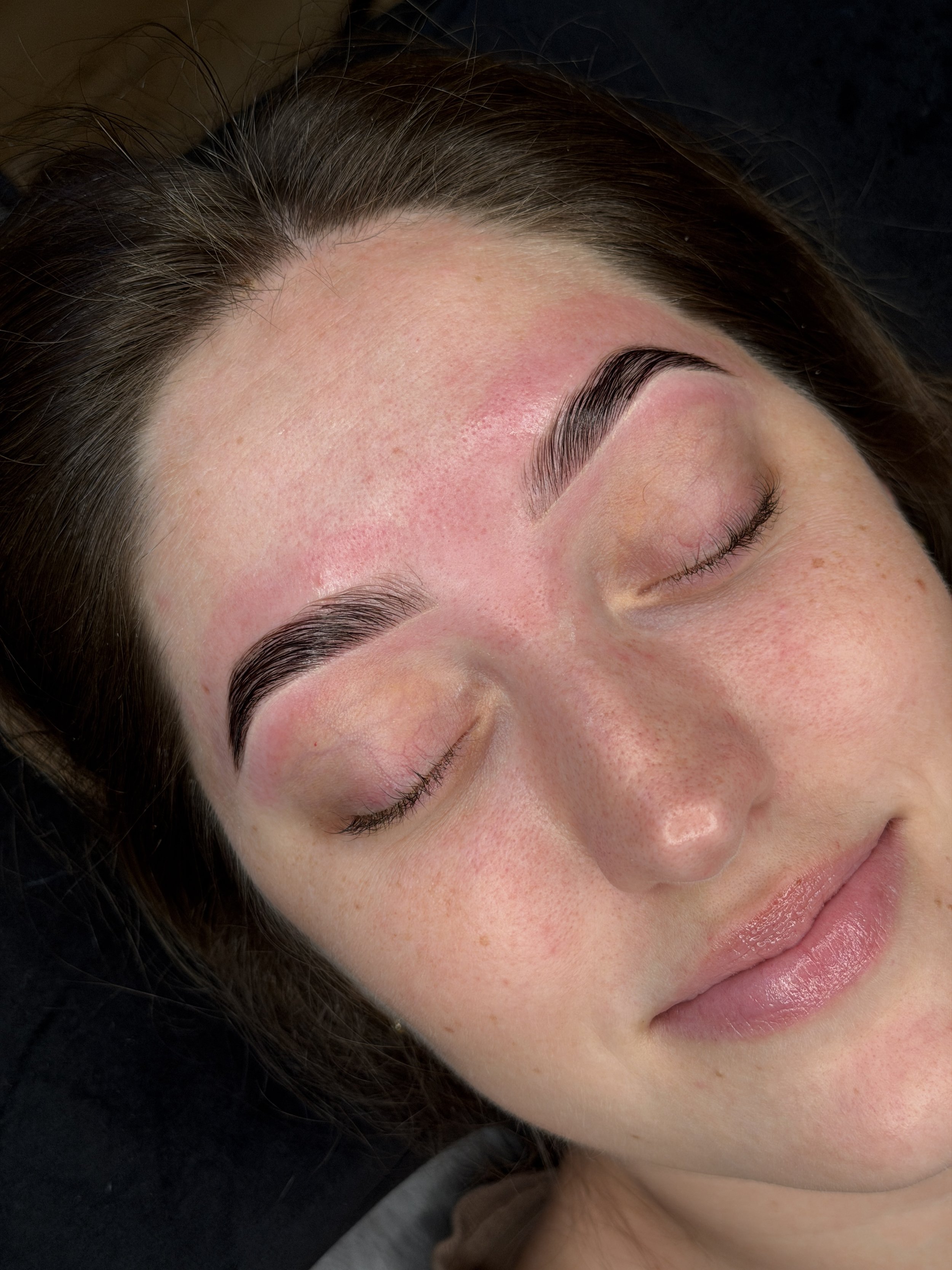 Close-up of a woman with well-groomed eyebrows and smooth skin, sleeping or relaxing with her eyes closed.