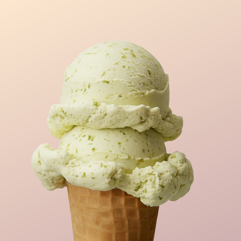 A scoop of green mint ice cream in a waffle cone against a light pink background.