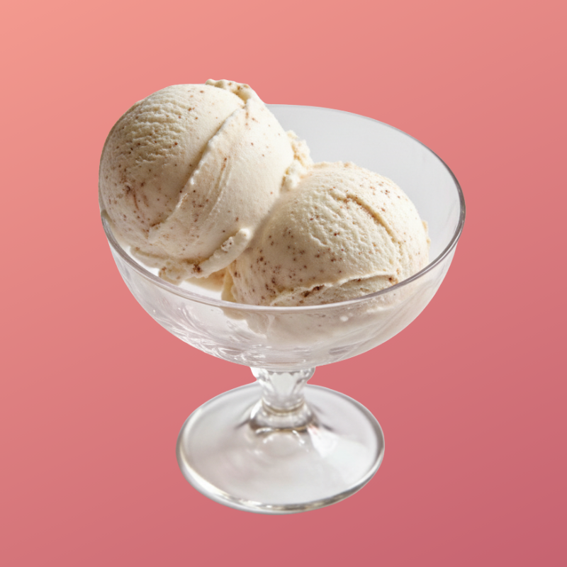 Two scoops of vanilla ice cream in a clear glass bowl against a pink background.