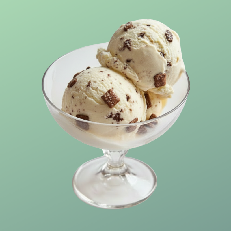 Three scoops of vanilla ice cream with chocolate chunks in a glass bowl against a pastel green background.