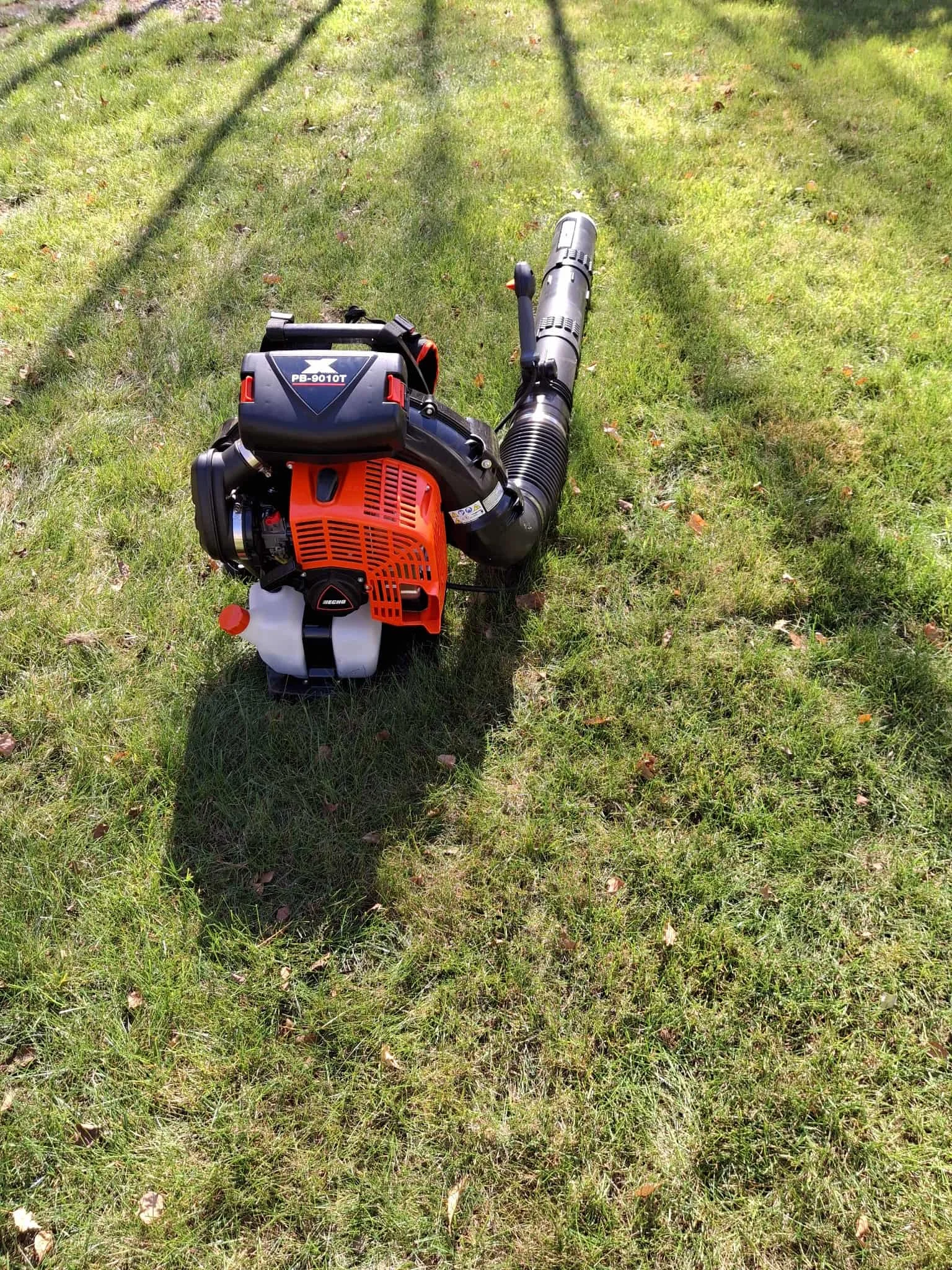 A gas-powered leaf blower resting on green grass.