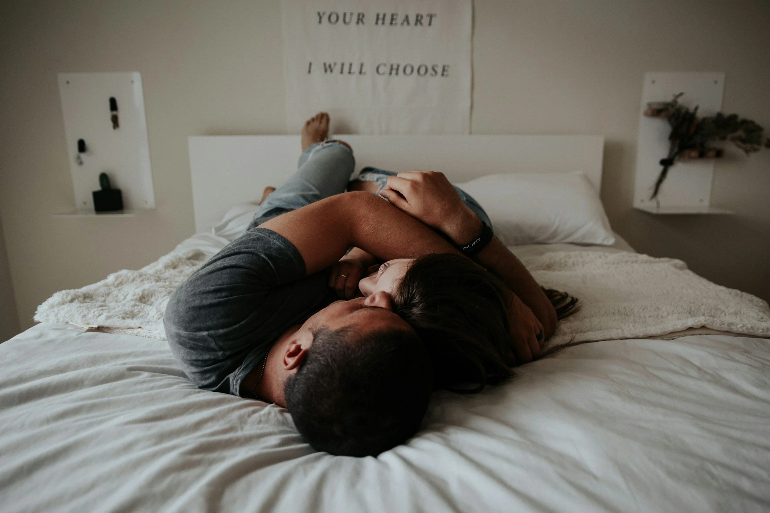 A couple cuddling on a bed in a bedroom.