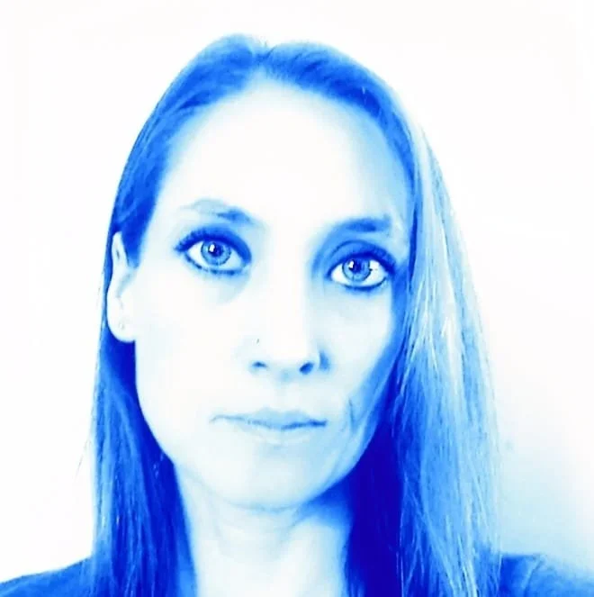 A woman with blue-toned hair and eyes looking at the camera.