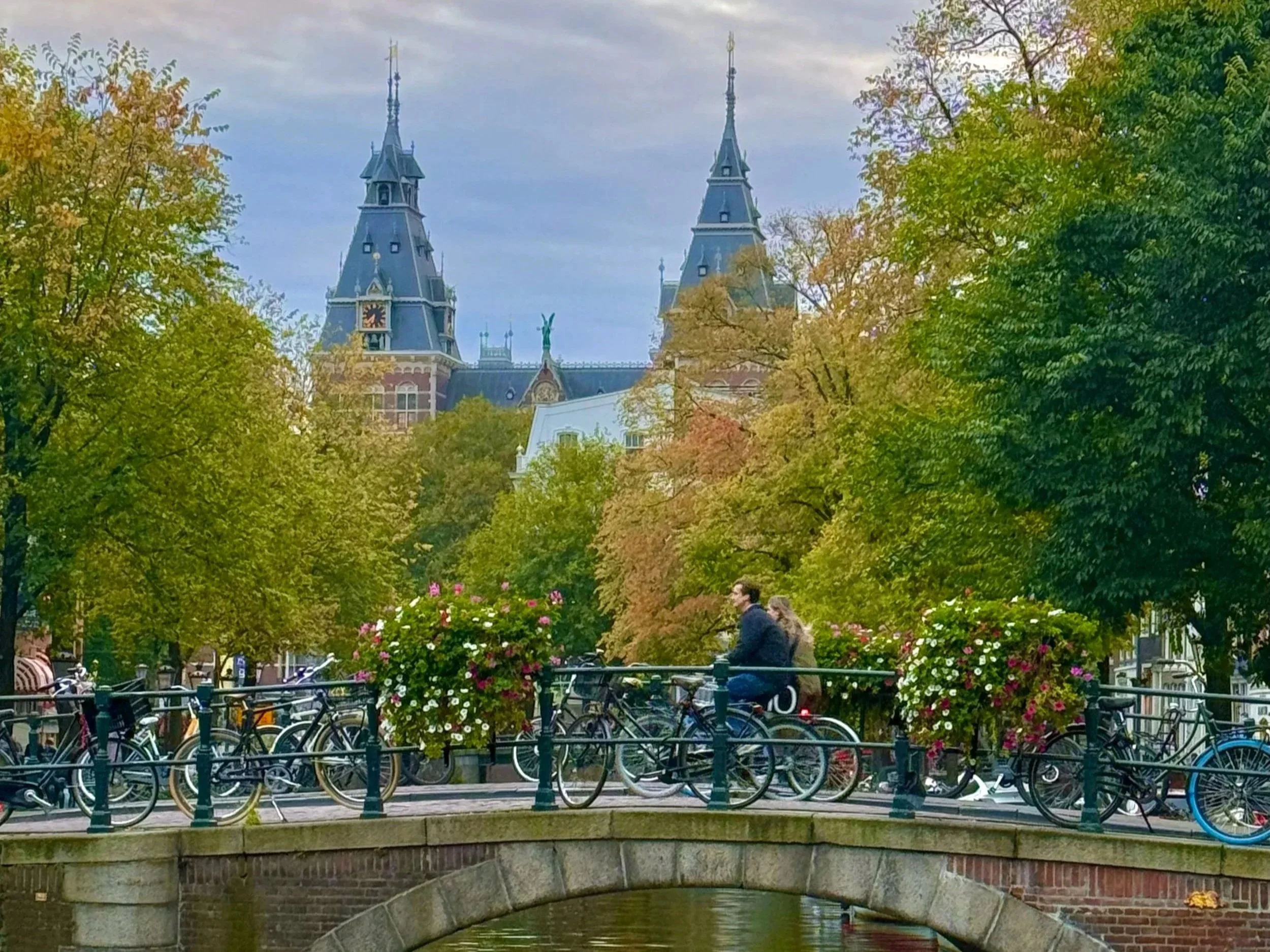 Cyclists crossing the bridge over one of Amsterdam's famous canals with the Rijksmuseum in the background.
