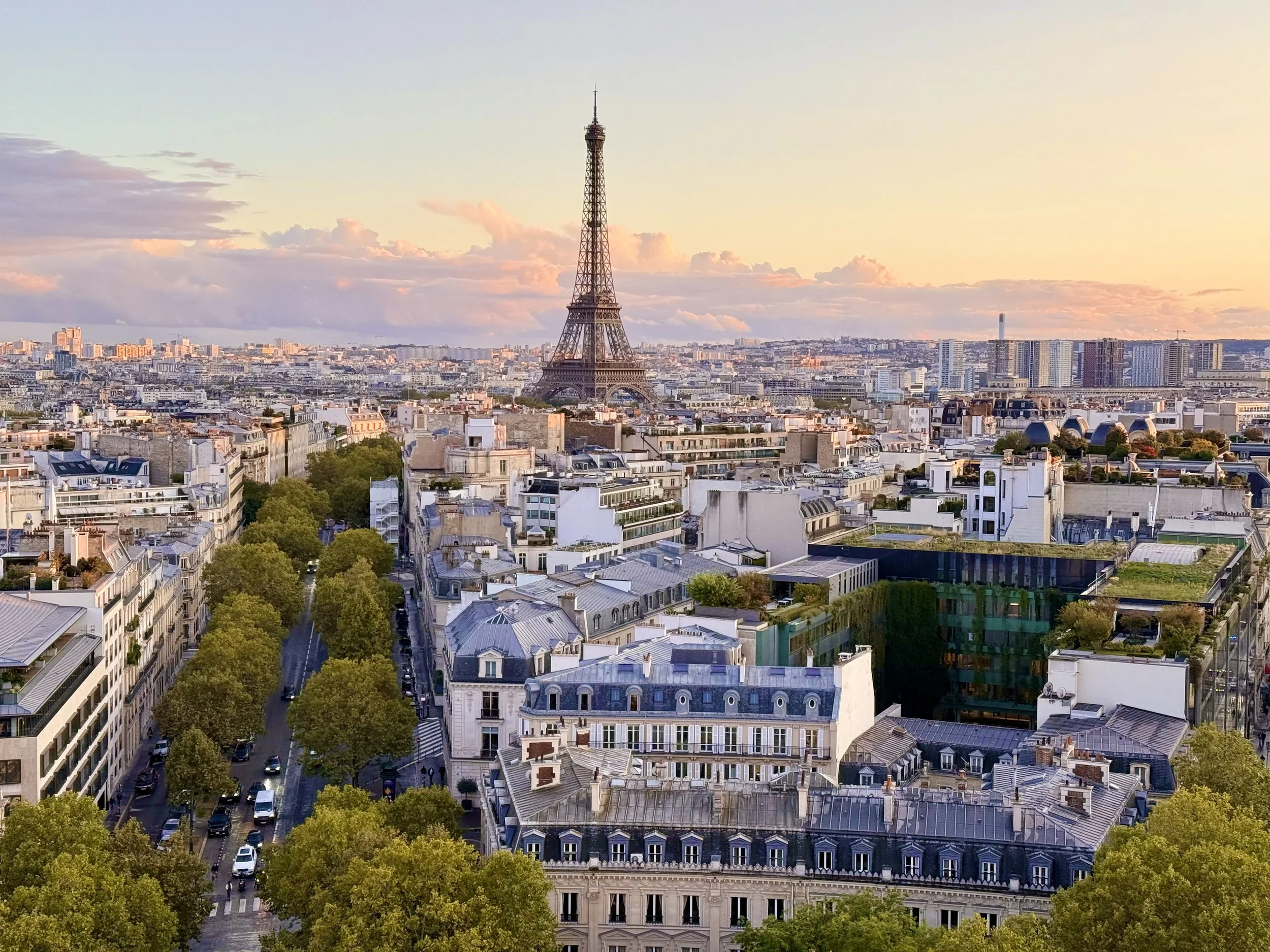 View of Paris with the Eiffel Tower in the distance during sunset on top of the Arc de Triomphe.