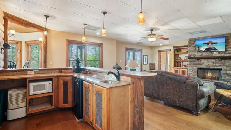Open-concept living room and kitchen with wood accents, a fireplace, and a mounted TV