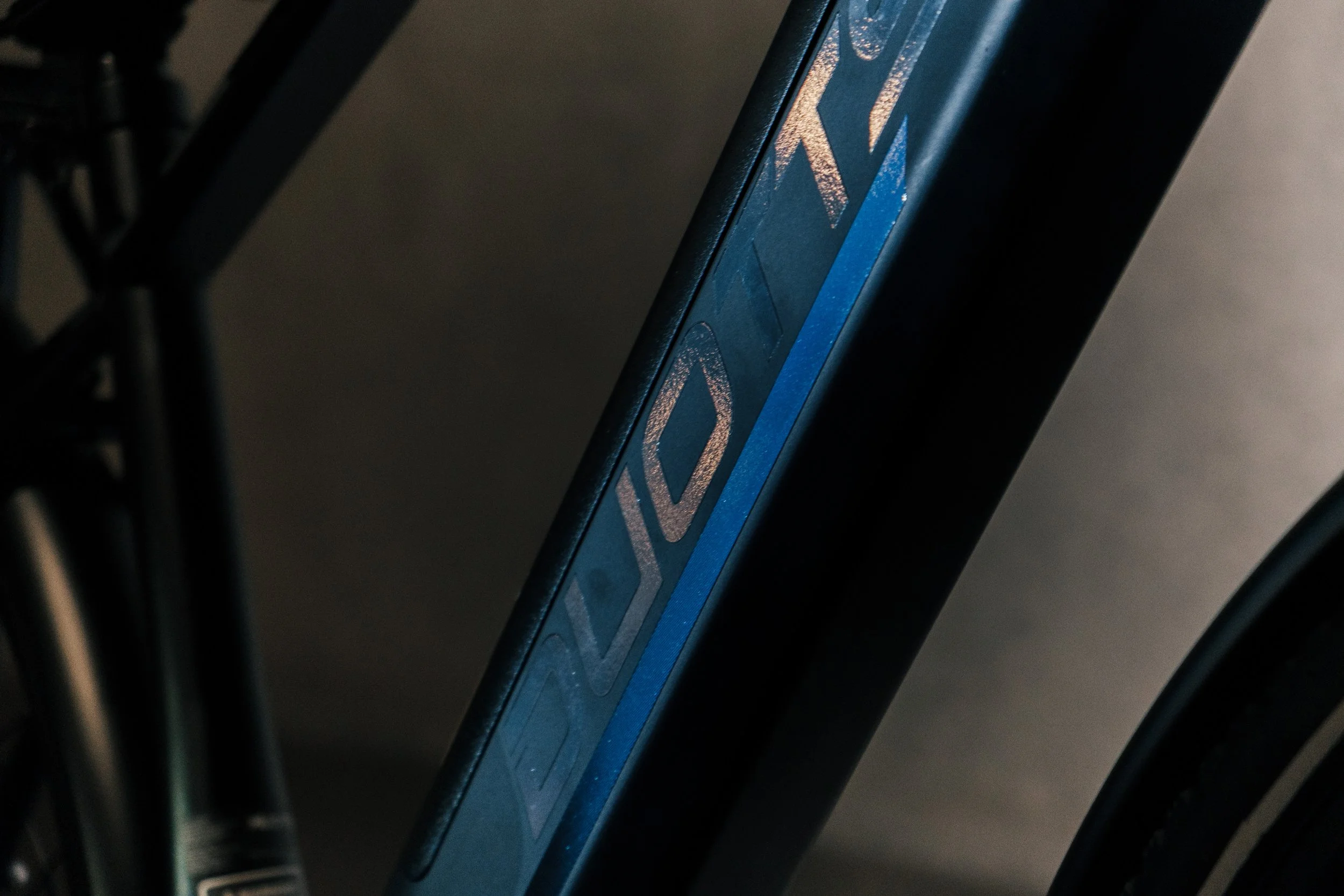 Close-up view of a section of a bicycle frame with a label, showing part of the wheel and some black structural elements.