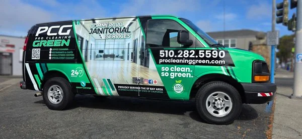 Pro Cleaning Green janitorial service van parked at a street corner with contact information on the side.