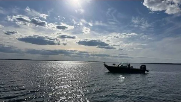 A boat floating on a body of water with a cloudy sky overhead