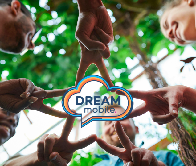 Group of diverse people forming a star shape with their fingers around a cloud-shaped sign reading 'DREAM mobile' outdoors with trees in the background.