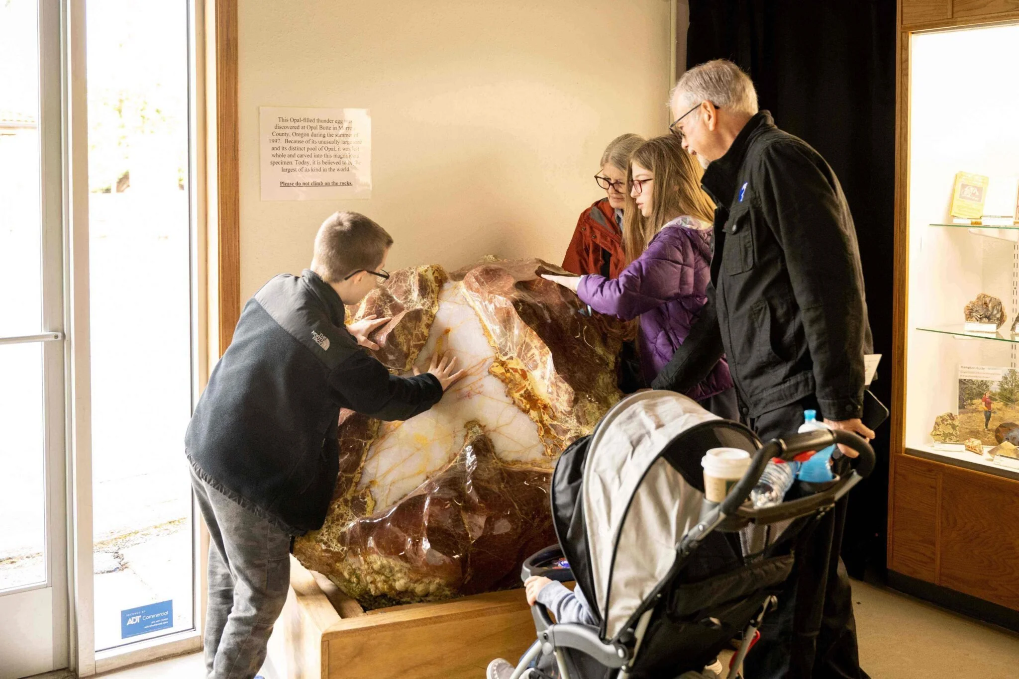Grandmother, grandfather, and grandkids touch a giant, polished thunderegg.