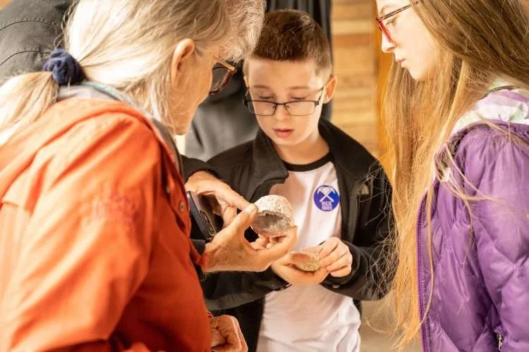 An older person explains geodes to a young child with glasses.