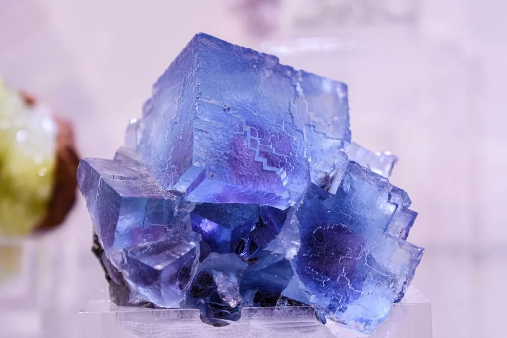 Cubic fluorite crystal cluster showing translucent blue and purple tones and stepped crystal faces.