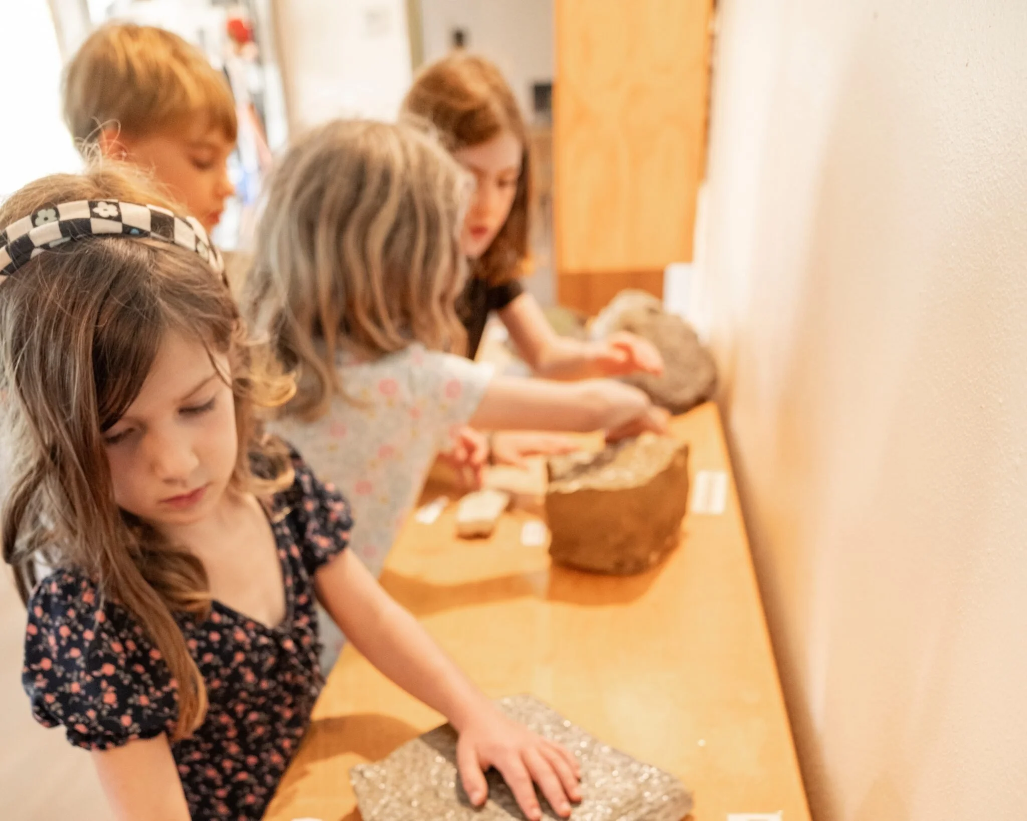 Students on a guided tour touch the rocks on display at Rice museum