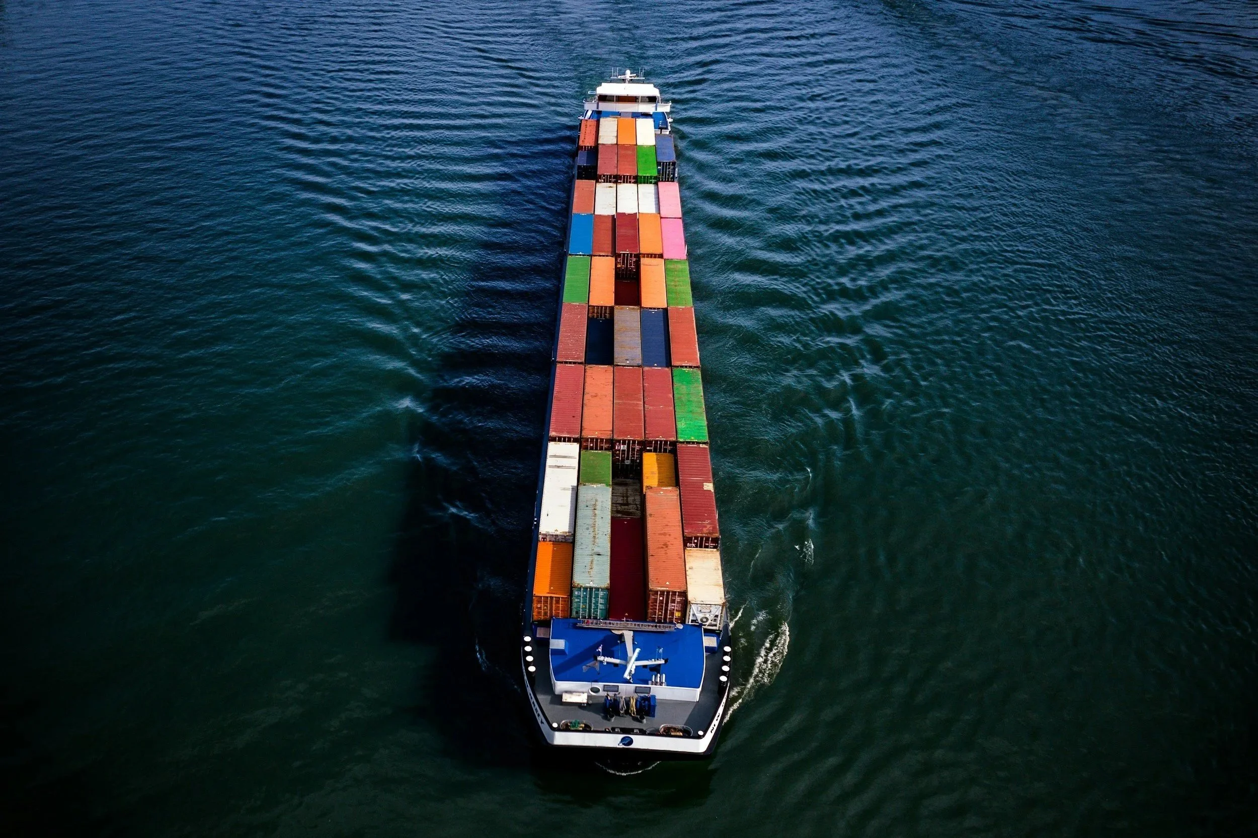 A cargo ship with numerous colorful shipping containers sailing on the ocean.