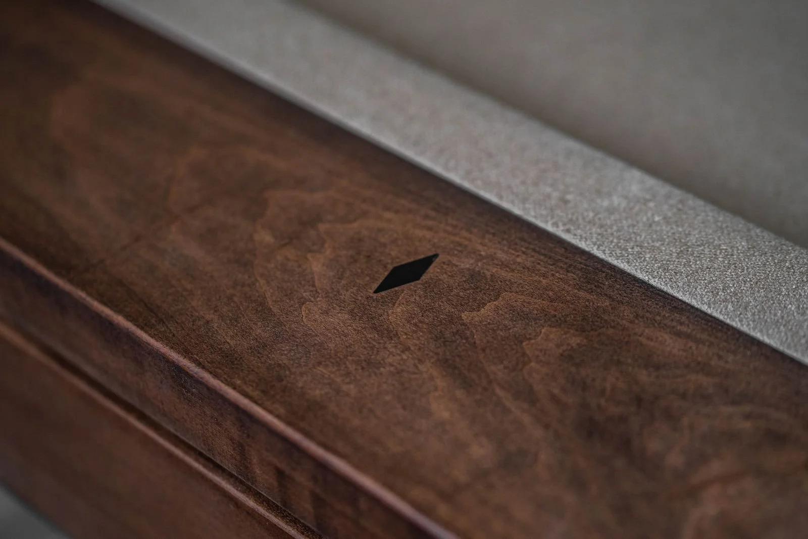 Close-up of a wooden surface with a small, black diamond-shaped symbol in the center.