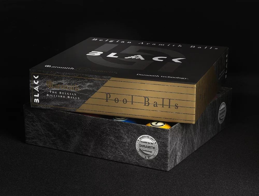 A box of Belgian pool/billiard balls labeled 'BLACK' and 'Pool Balls' with black and gold packaging, containing a set of billiard balls.