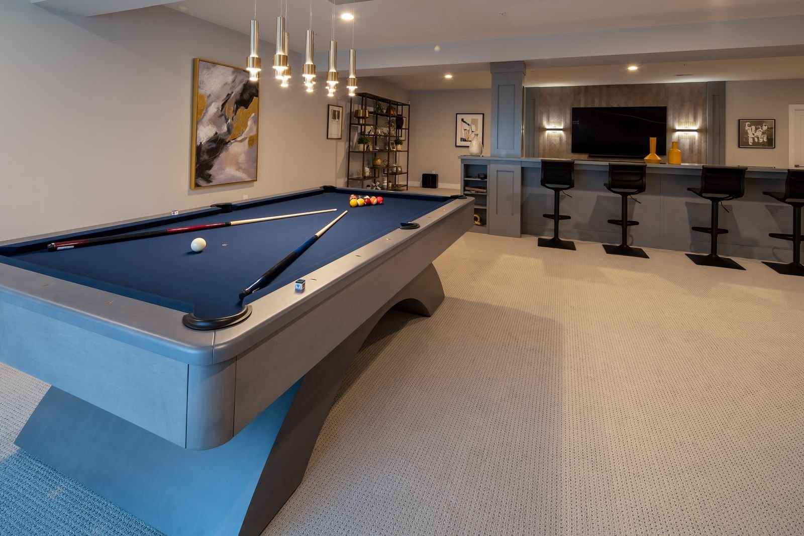 Indoor game room with pool table and a bar area with four black barstools