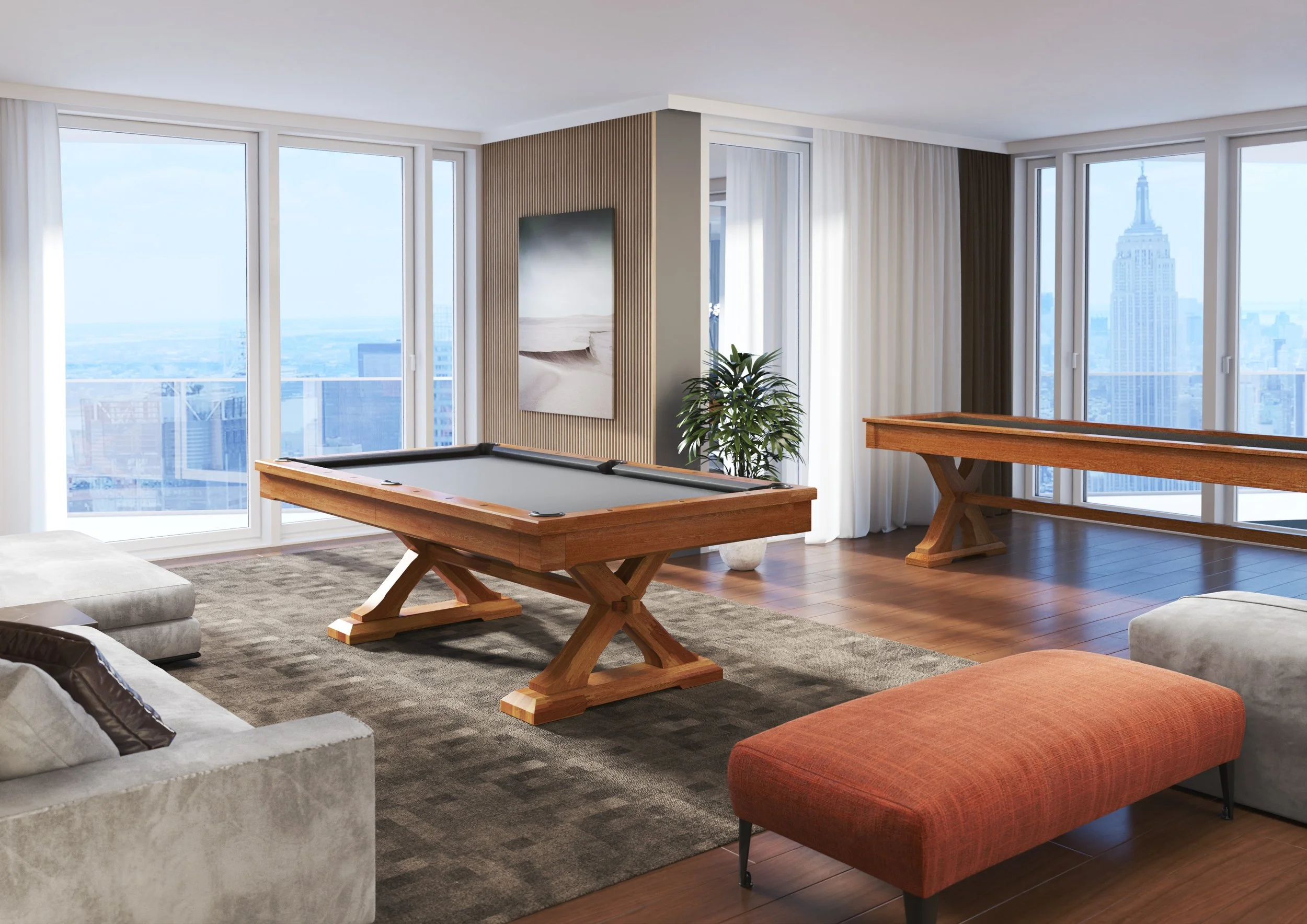 Living room with large windows showing Manhattan skyline, including Empire State Building. Features include a pool table, plant, framed abstract art, orange ottoman, and a sectional sofa.
