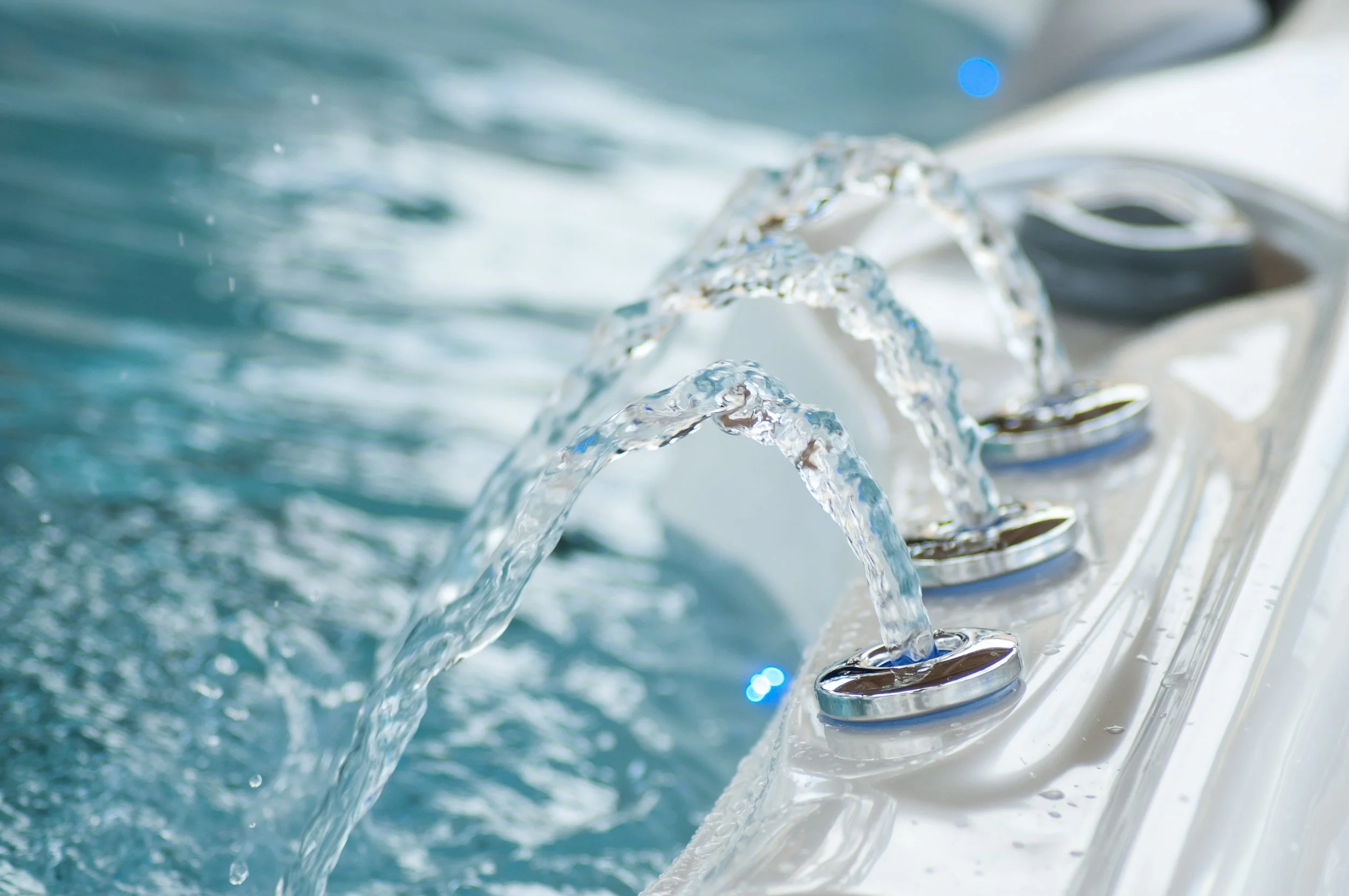 Close-up of water flowing from control dials of a chrome faucet