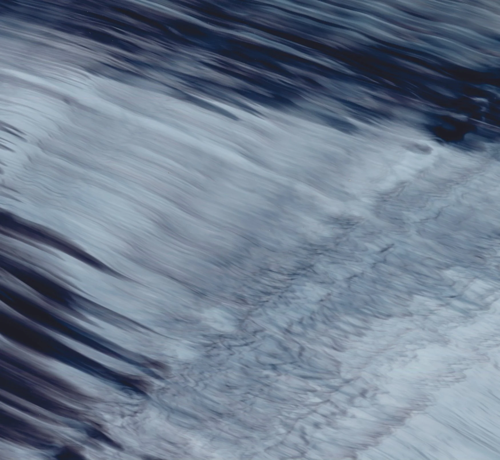 Close-up of a flowing body of water, likely a river or waterfall, with motion blur creating a smooth, streaked appearance.