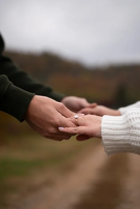 A man and woman holding both of their hands outside.