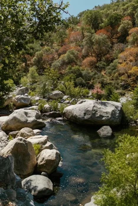 Rocks around blue water with orange and green trees.