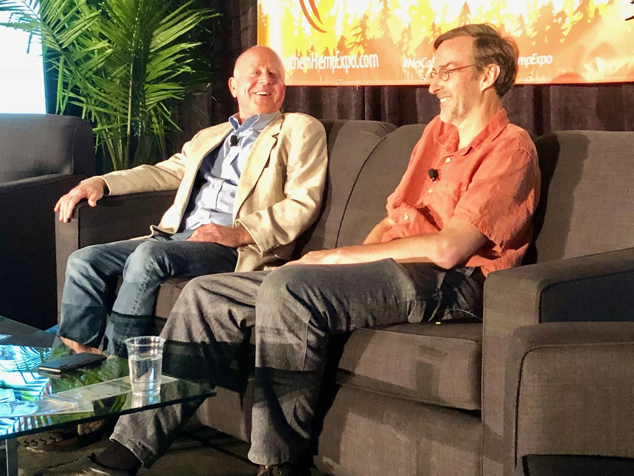 Pioneering hemp farmer Joe Hickey and John Roulac, founder of Nutiva and Re: Botanicals, share a laugh on stage at the Southern Hemp Expo Business Conference.