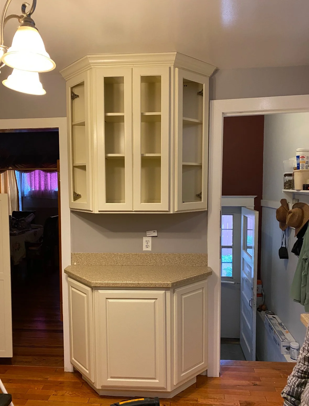 Kitchen corner with white cabinets, a countertop, and a small pantry or storage area by the door.