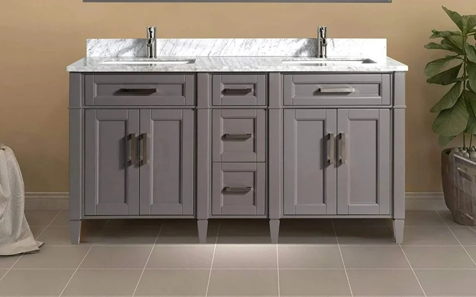 Gray bathroom vanity with two sinks, a marble countertop, and multiple drawers and cabinets, with tile flooring and a potted plant on the right.