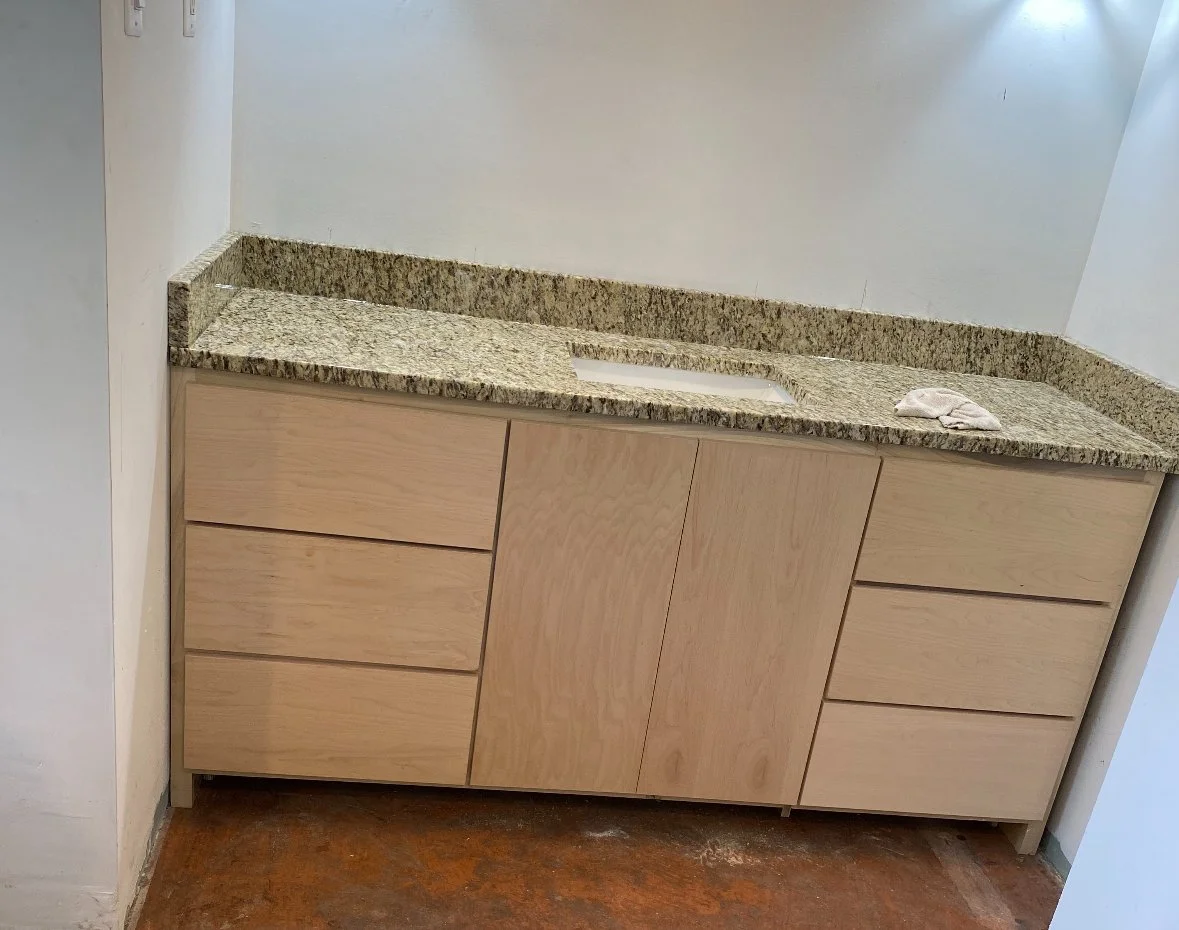 Kitchen cabinet with granite countertop, integrated sink, and no visible fixtures