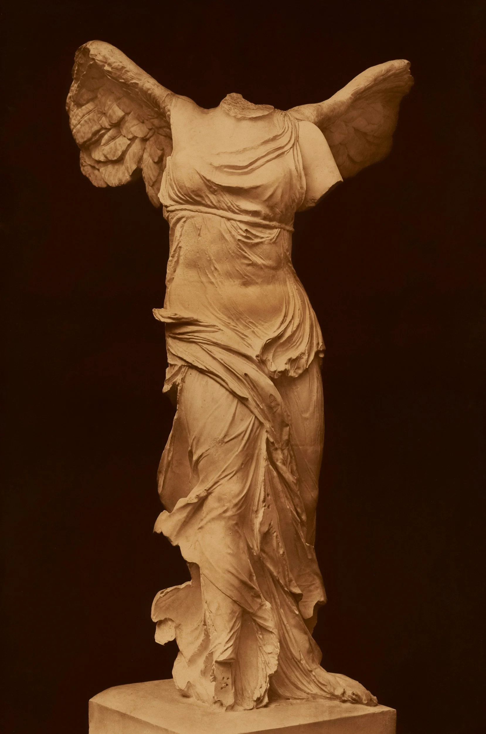 Ancient marble sculpture of a headless female figure with broad wings.