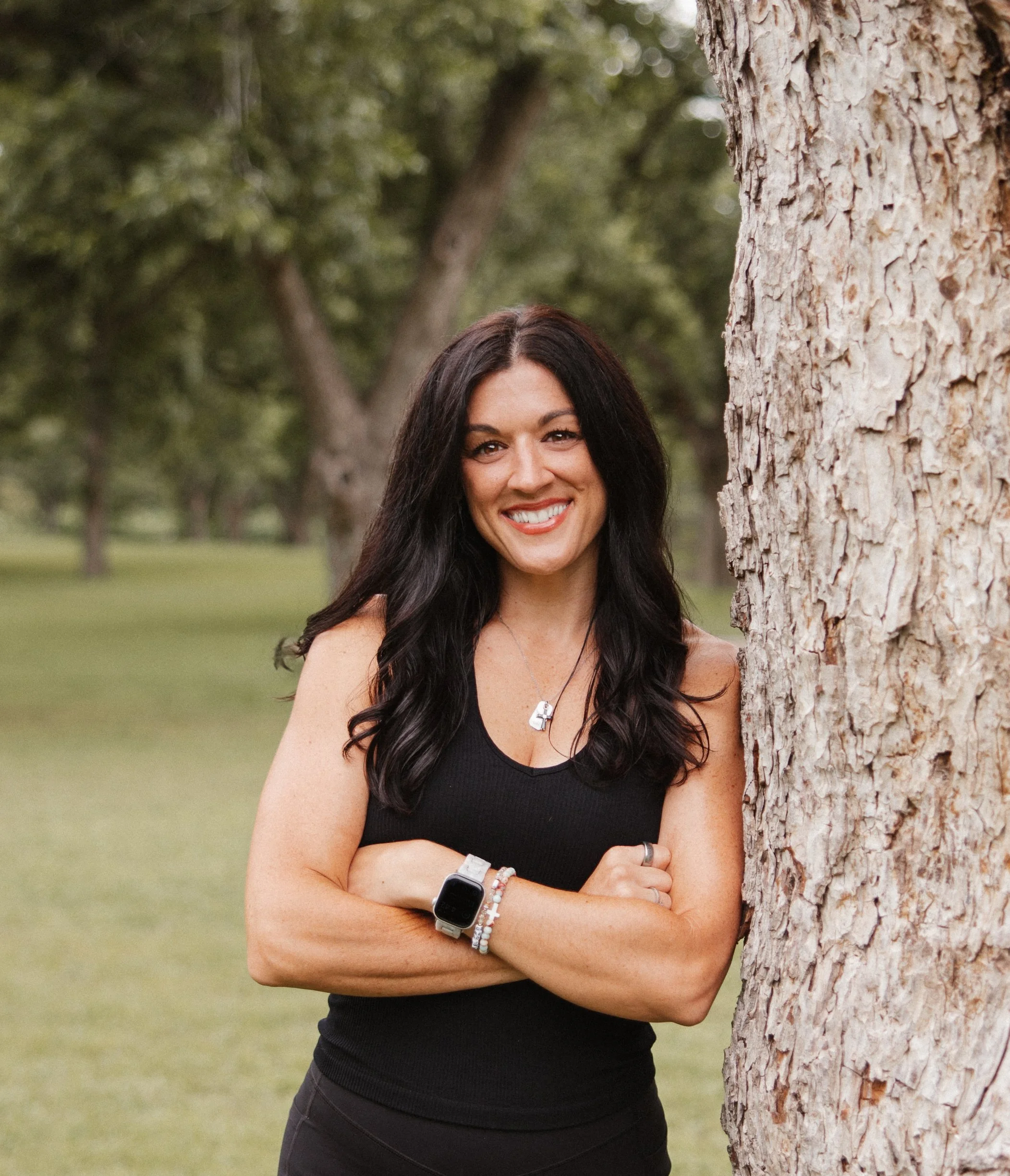 Close-up portrait of a woman with long black hair, fair skin, and a bright smile, wearing a black top.