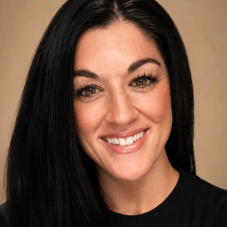 Close-up portrait of a woman with long black hair, fair skin, and a bright smile, wearing a black top.