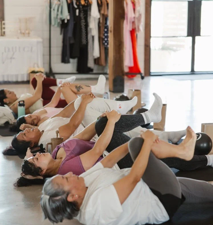 Group of women doing yoga or stretching exercises on mats in a fitness studio or gym.