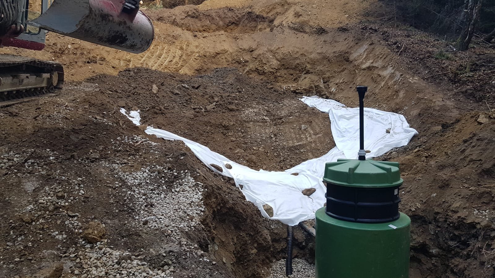 Ausschnitt einer Baustelle mit Erde, weißen Abdeckungen und einem Kabelstrang.
