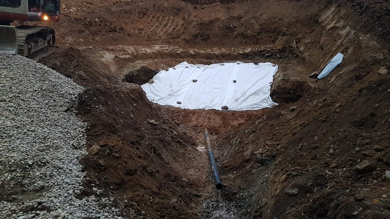 Ein Baugrube auf einer Baustelle mit einem weißer Plane bedeckt