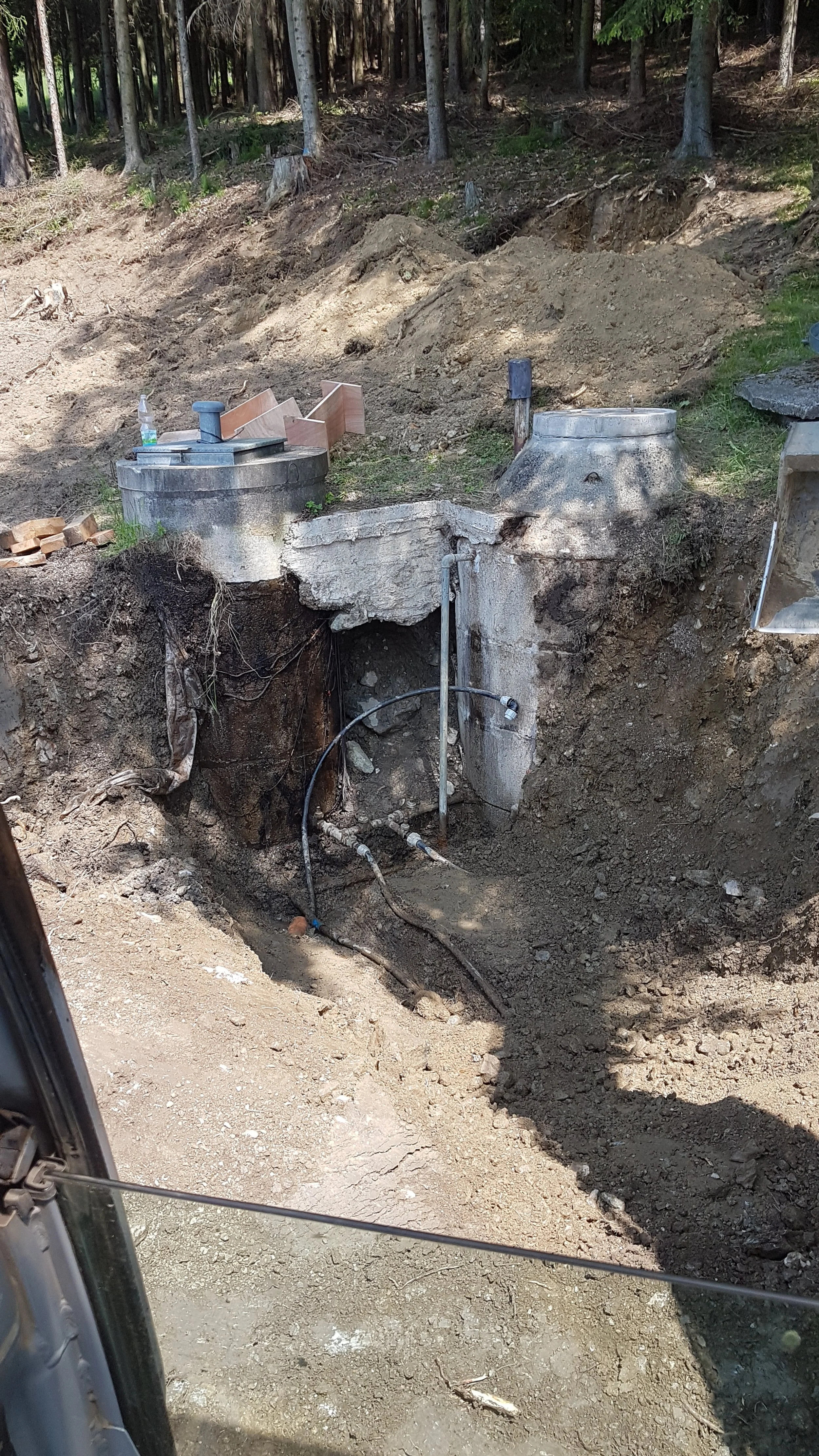 Bau einer unterirdischen Wasserleitung im Wald mit gegrabenen Graben, Rohren und Betonfundamenten.